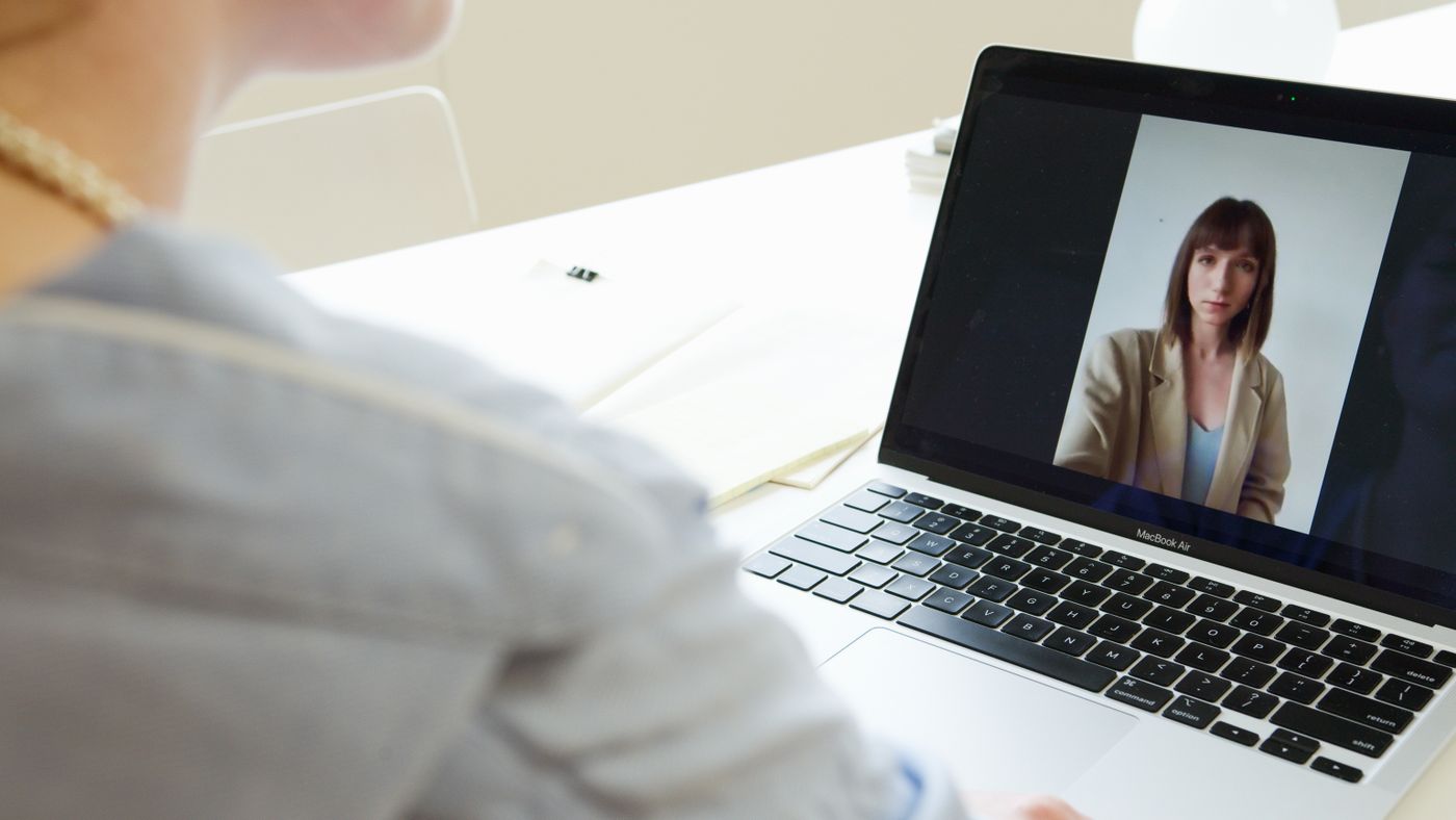 A student sitting at a laptop mid-video-call, the person interviewing her filling the screen